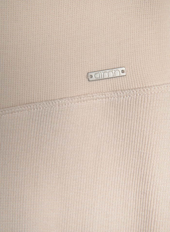 Beige ribbed wool-blend knit fabric shown in a close-up with a silver aim'n metal logo badge.