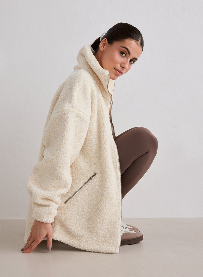 A model wearing an Almond White Pile Jacket crouching [M-174cm]