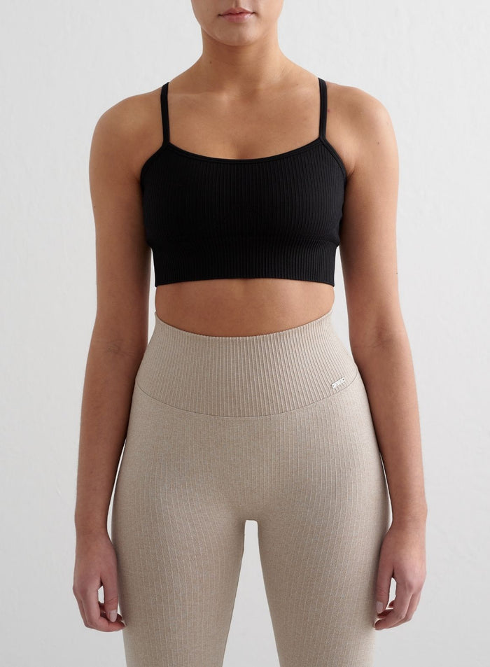 Black ribbed seamless strap bra by aim'n featuring thin straps, styled with beige high-waisted leggings.