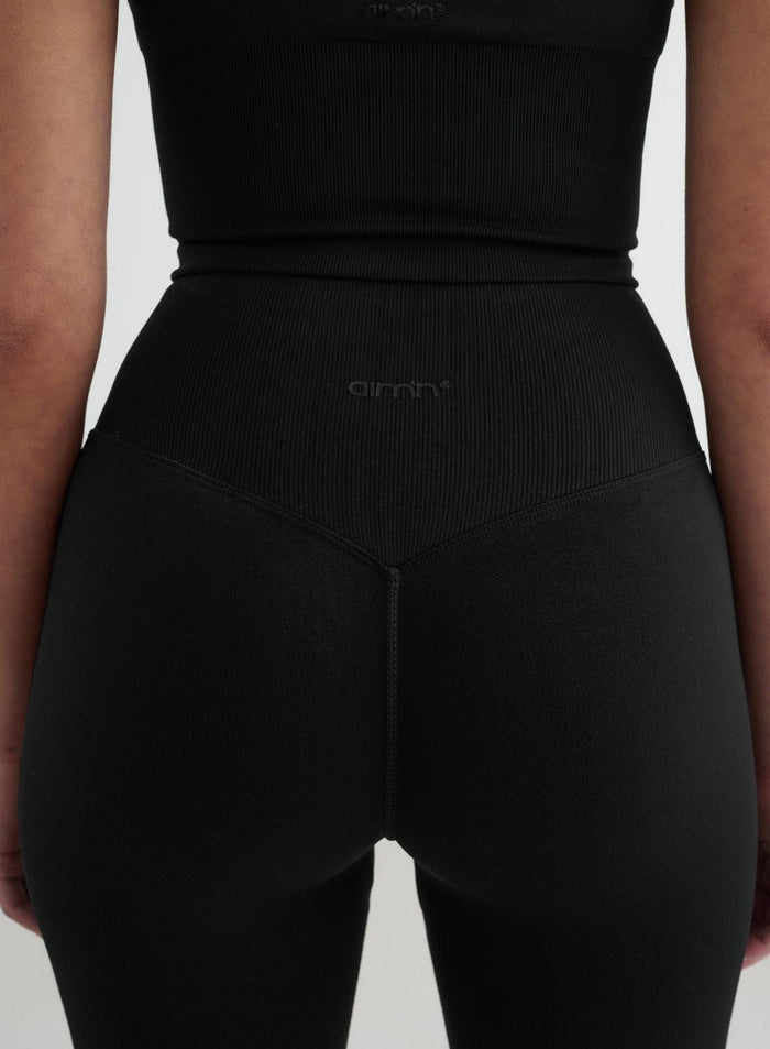 Black high-waisted seamless flare tights with a ribbed V-shaped waistband and tonal aim'n logo.