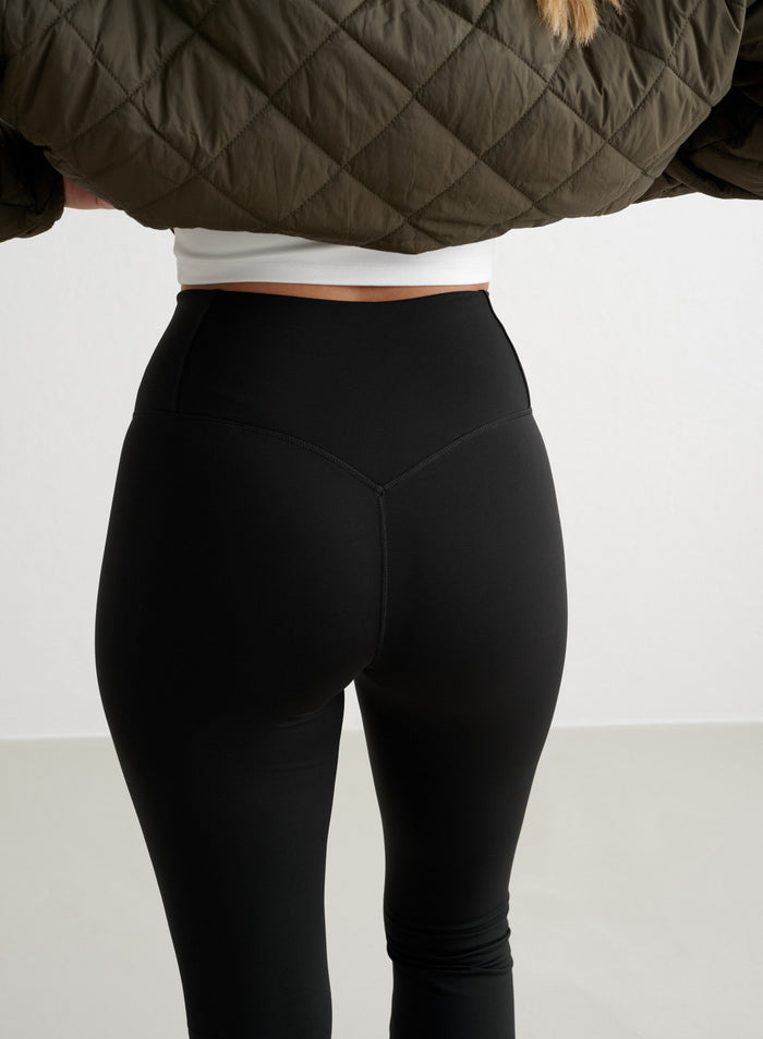 Back view of black high-waisted Warming Flare Tights by aim'n showing shaped seam details. [S-175cm]