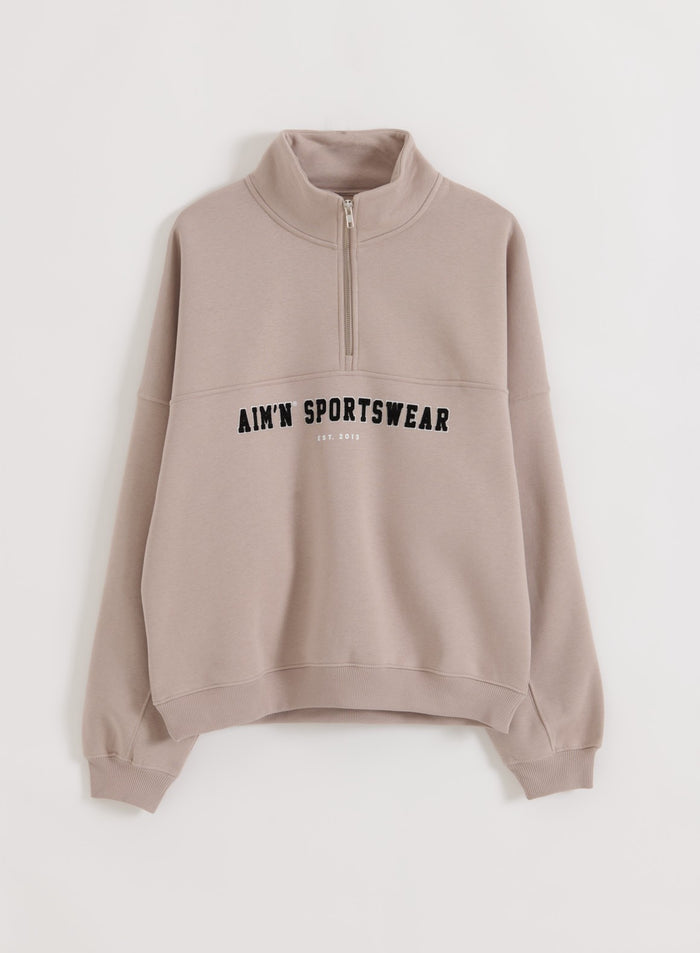 Dark clay Varsity Sweat Half Zip featuring a stand collar and varsity aim'n embroidery on the chest.