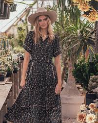 Woman in floral dress & hat in greenhouse