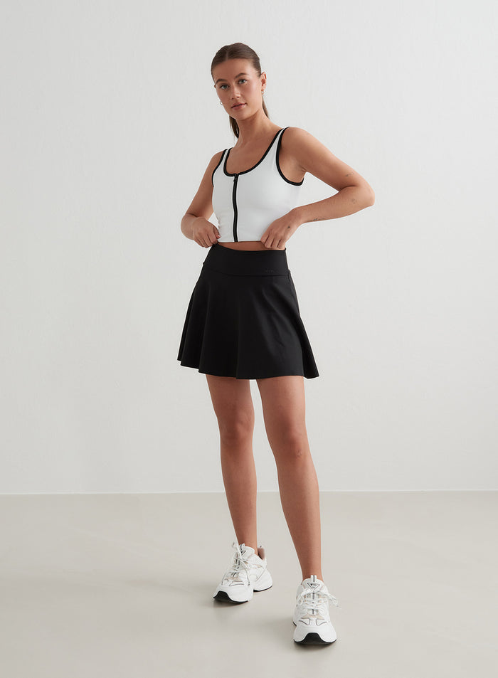 White aim'n Sense Zipped Bralette with black contrast edges and a black tennis skirt for an active look. [S - 175 cm]