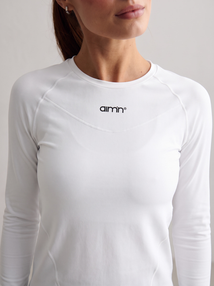 Close-up of a model wearing the white Soft Basic Long Sleeve with the aim'n logo [S-174 cm]