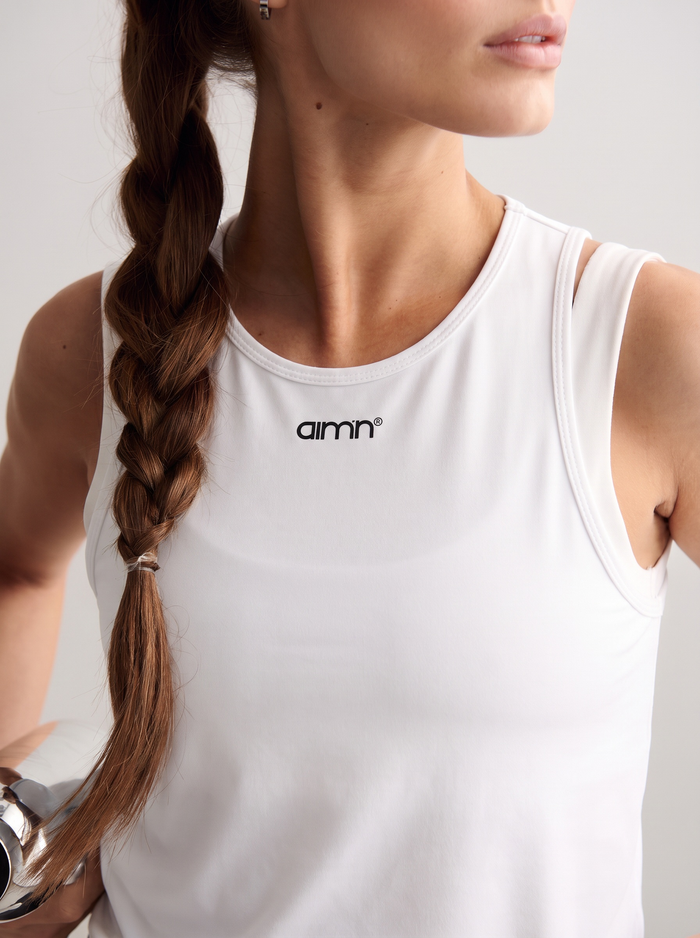 Model wearing white Soft Basic Singlet with a round neckline and printed aim'n logo [S-174 cm]